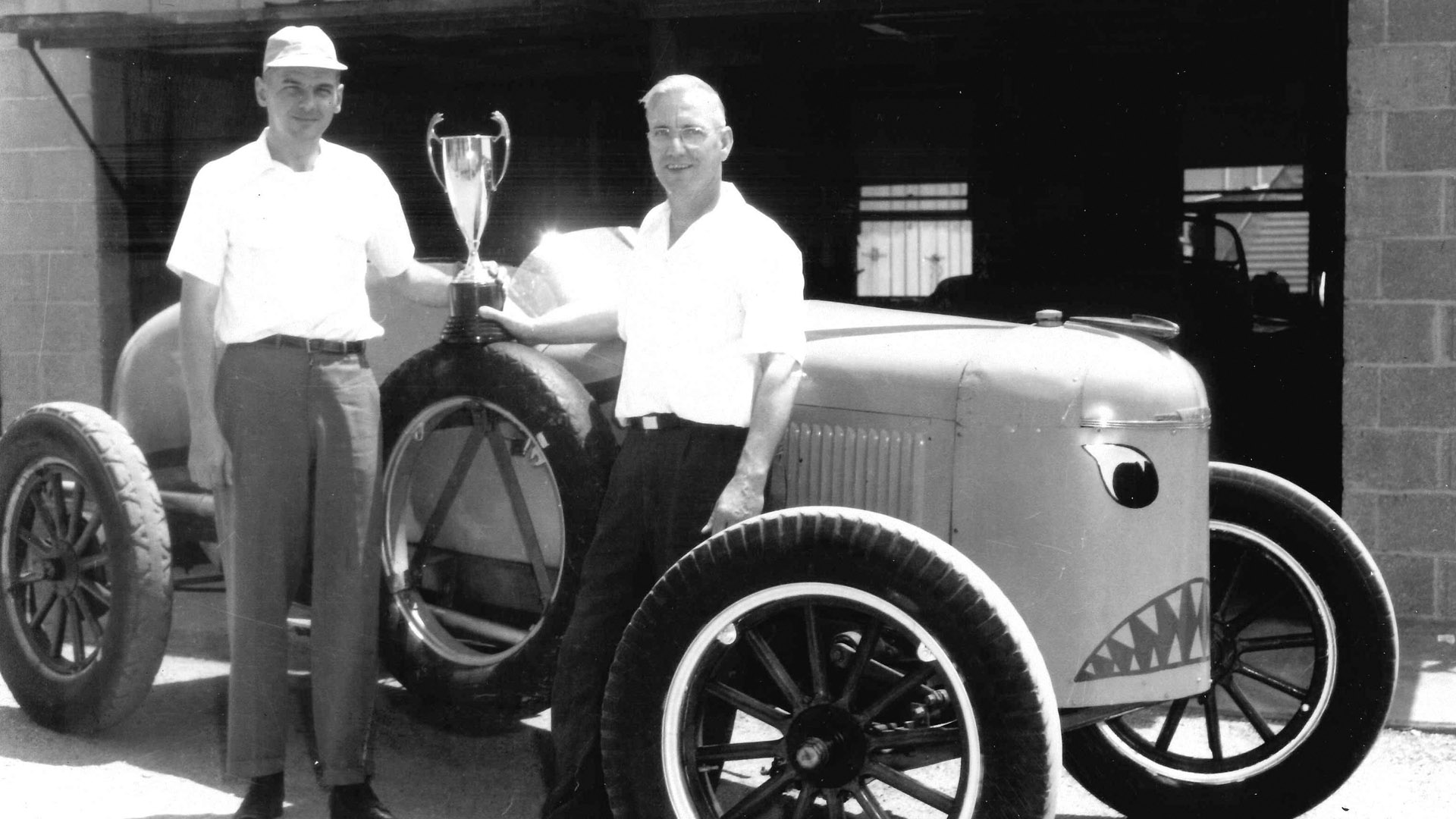 Black and white photo of racing car and two men