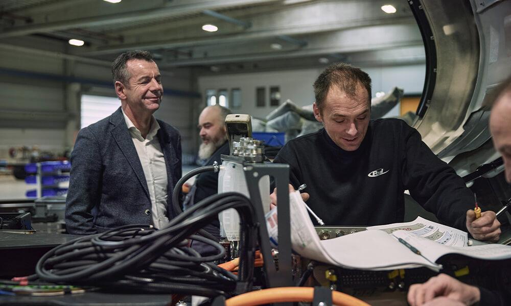 Person standing in front of hydrogen plant with arms crossed