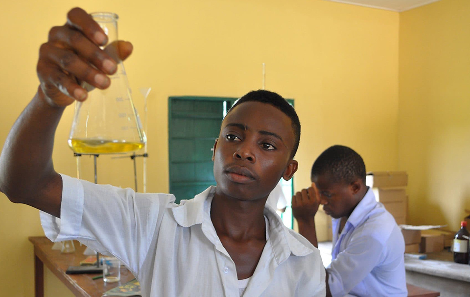 Boy holding a connical flask with yellow solution within it